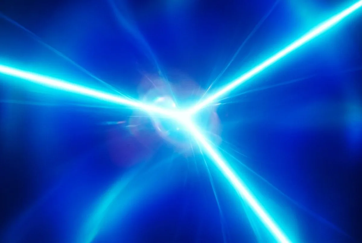 Three beams of blue light meeting at a single bright point