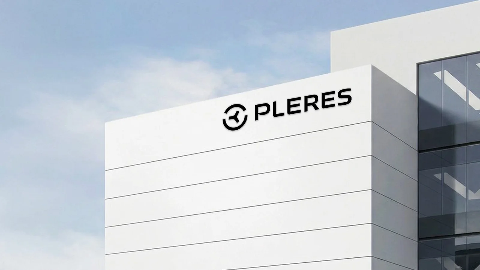 Black Pleres logo mounted high on the white facade of a modern office building against a pale blue sky